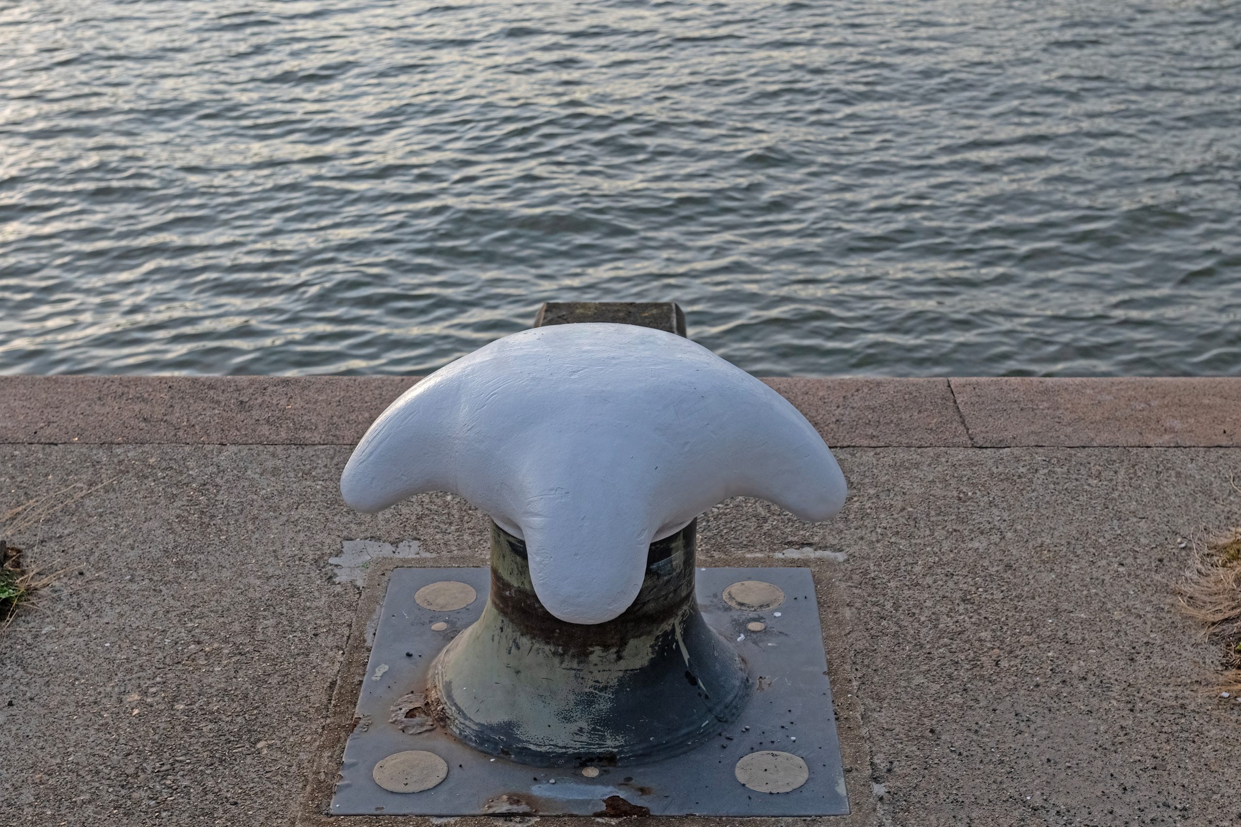 Mooring mast at the blue sea dock. Large bollard for mooring ships to the dock of the harbor.